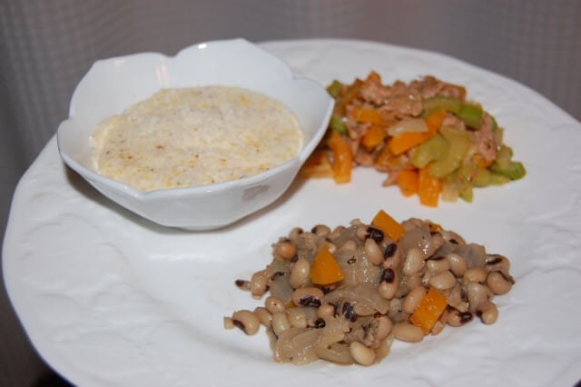 Plate of black-eyed peas for New Year's Day with a side of polenta and homemade stuffing.