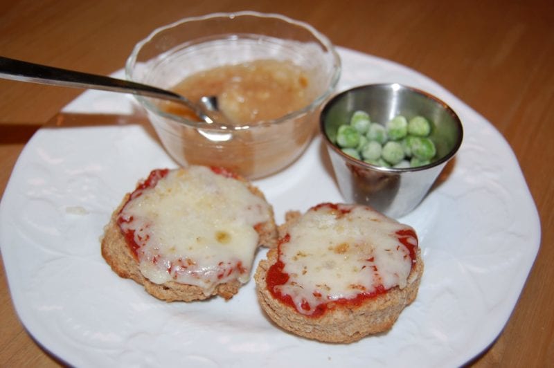 Homemade pizza biscuits, frozen peas, and a side of applesauce.