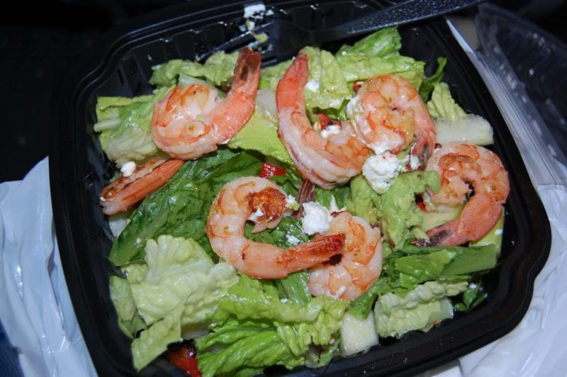 Cooked shrimp on top of a bed of lettuce.