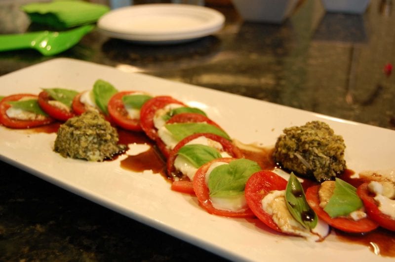 Caprese salad with pesto sauce on a plate.