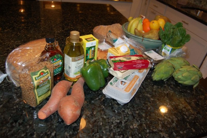Groceries from Earth Fare that include fresh produce, pasta, frozen blueberries, canola oil, butter, eggs, and more.