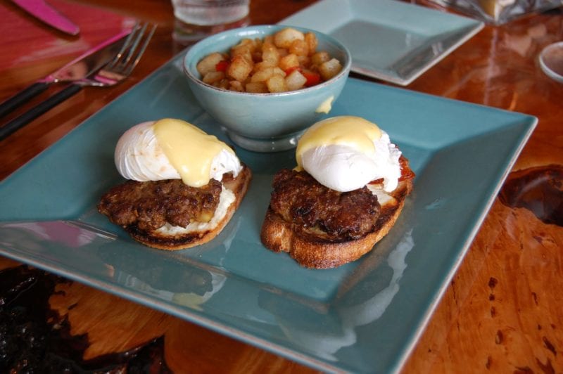 Eggs benedict with pasture-raised, house-crafted lamb sausage, warm chevre, romat tomatoes, and a poached egg over a toasted fresh-made baguette from Halcyon in North Carolina.