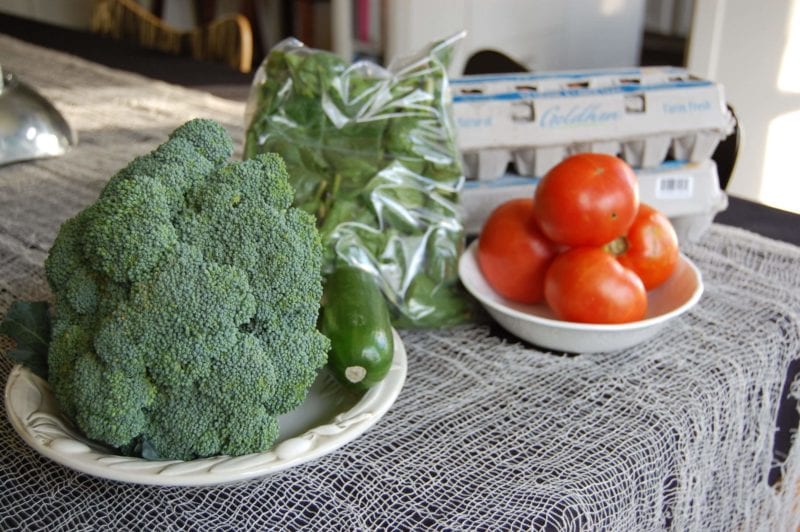 A plate of broccoli, cucumbers, tomatoes, eggs, and spinach.