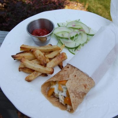 Homemade whole-wheat tortillas with cucumber salad and baked french fries with ketchup on a plate.