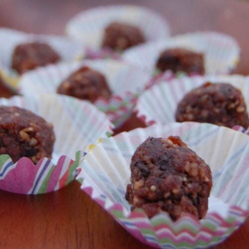 Seven homemade power balls sitting in decorative cupcake tins