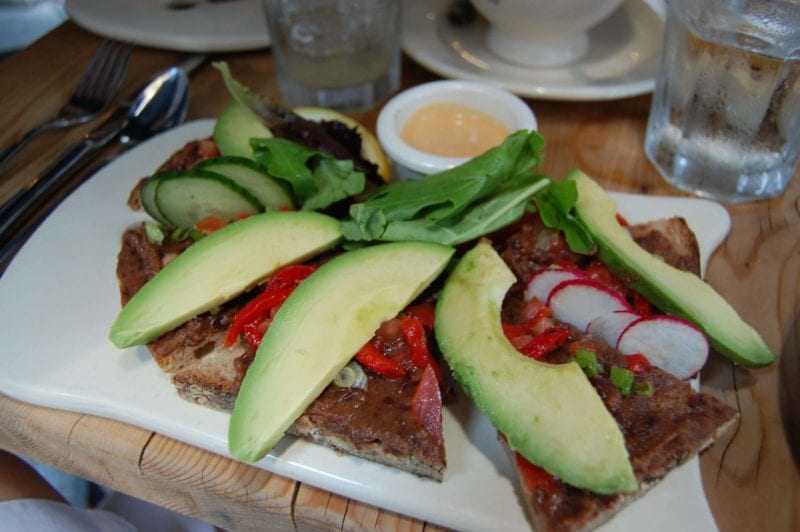 An open faced sandwich with black bean spread and avocado on whole-wheat bread.