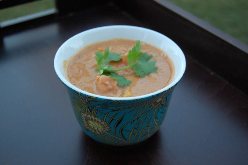 Homemade squash peanut soup topped with cilantry in a decorative bowl.